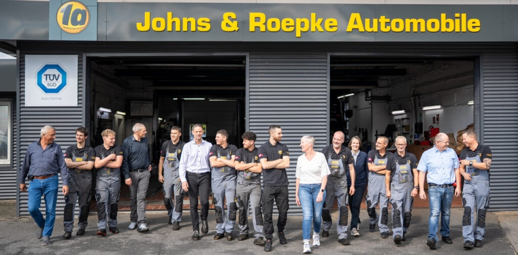 Das ganze Team eines Autohauses vor dem Betrieb